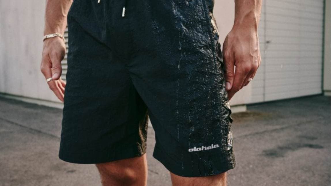 You can see a man from the waist to the knees. He wears black swim shorts.